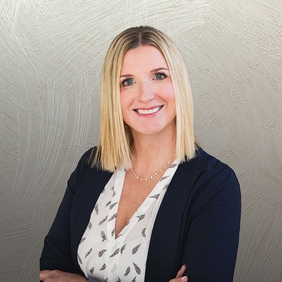 Professional woman smiling against gray background.