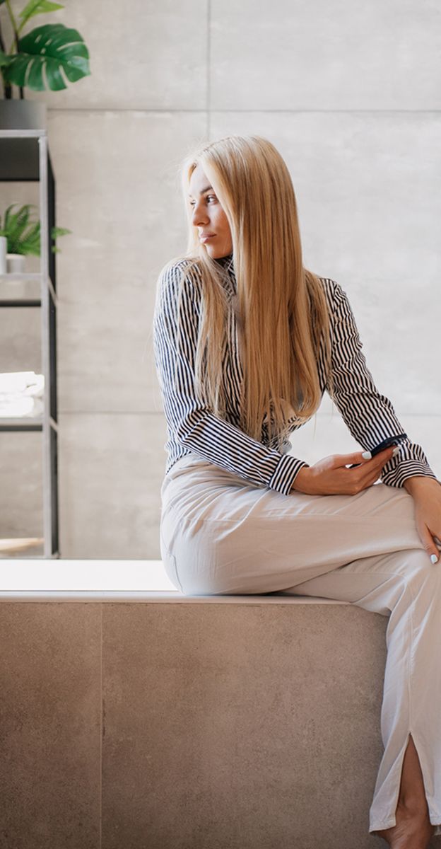 Woman sitting on a ledge in modern space.