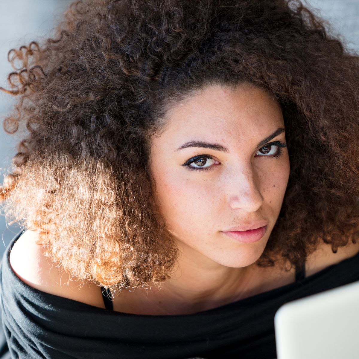 Woman with curly hair looking thoughtfully at camera.