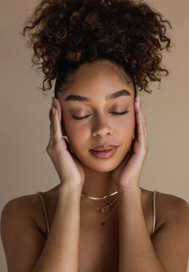 Woman with closed eyes holding her face gently.