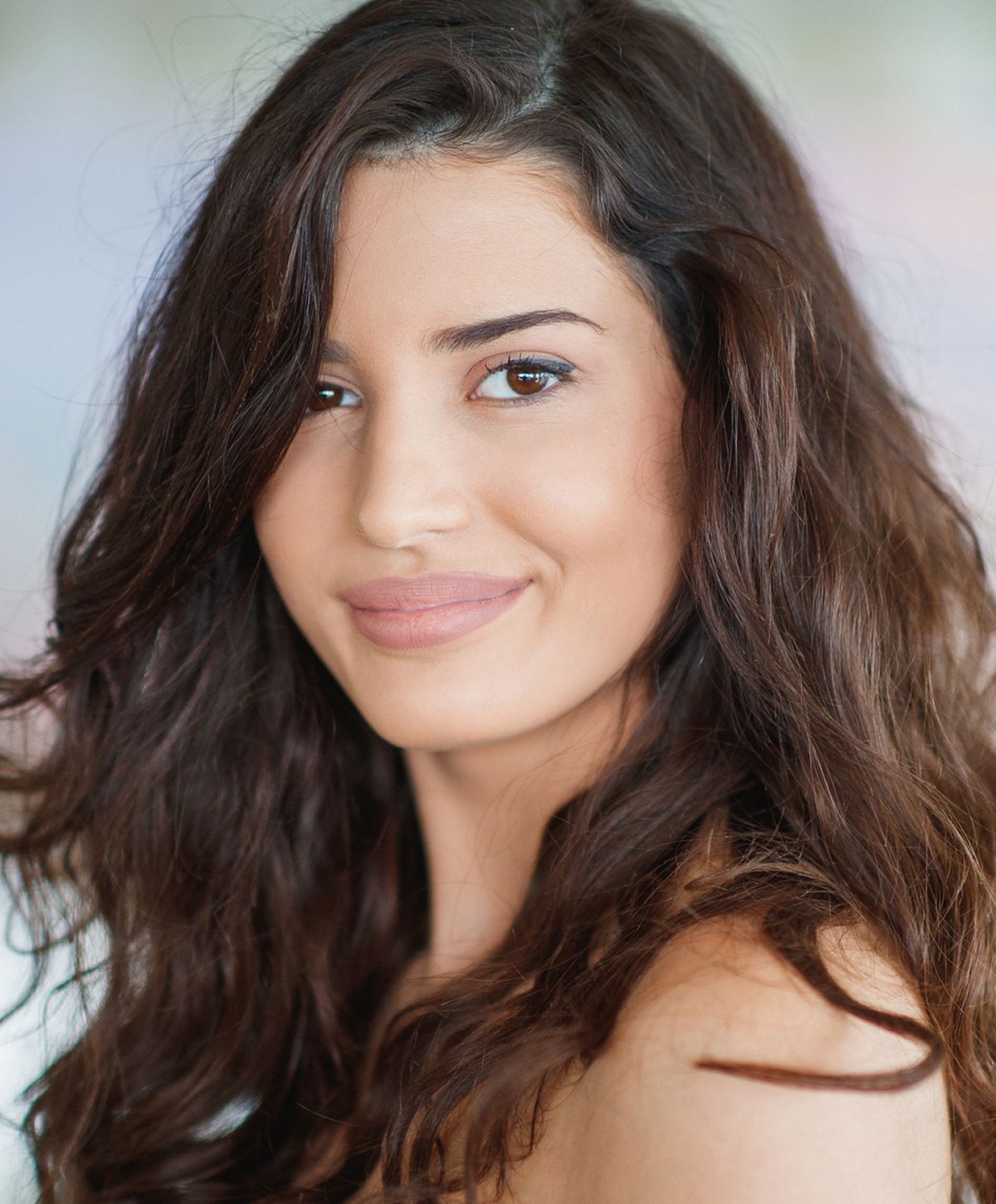 Smiling woman with long, wavy brown hair.