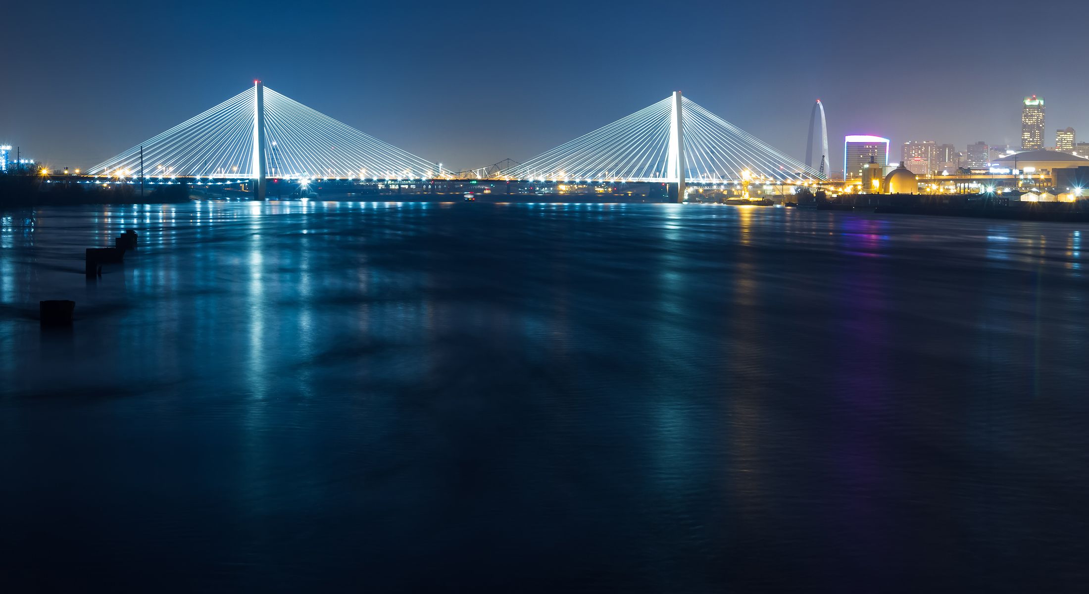Lit bridge reflecting in the water at night.