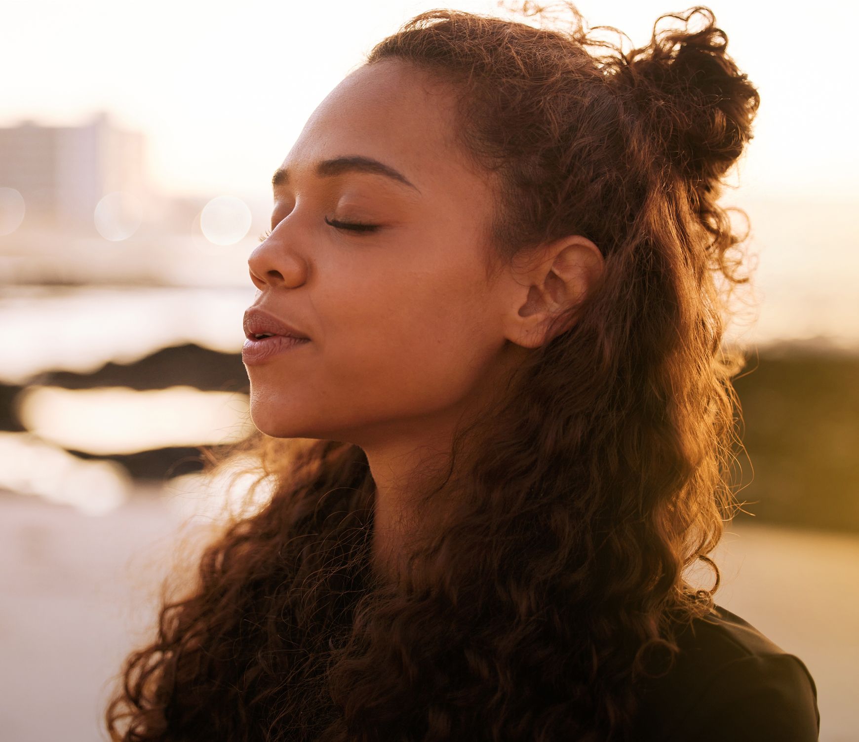 Woman with curly hair, eyes closed, serene expression.