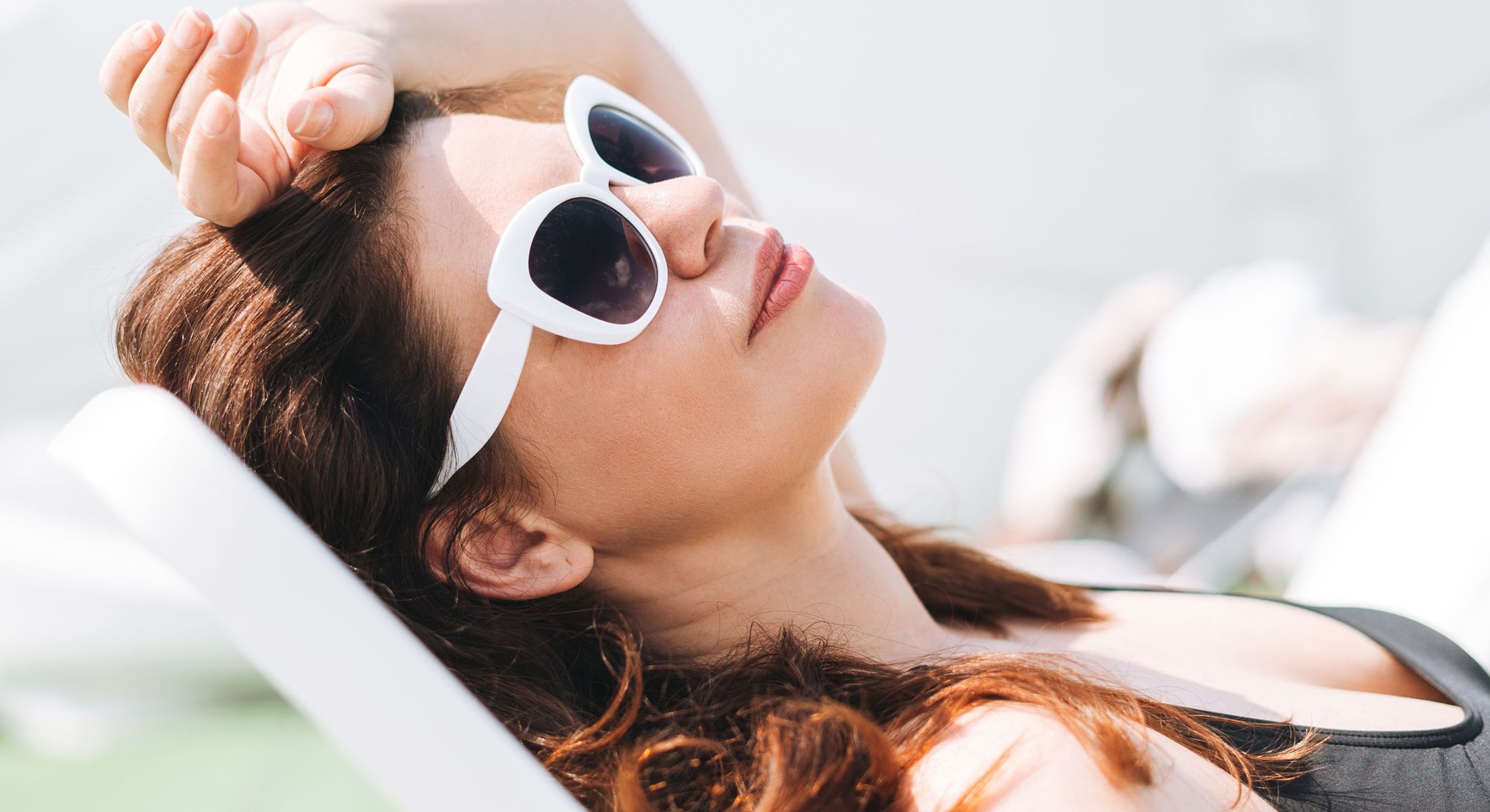 Woman relaxing in sunglasses sunbathing outdoors.