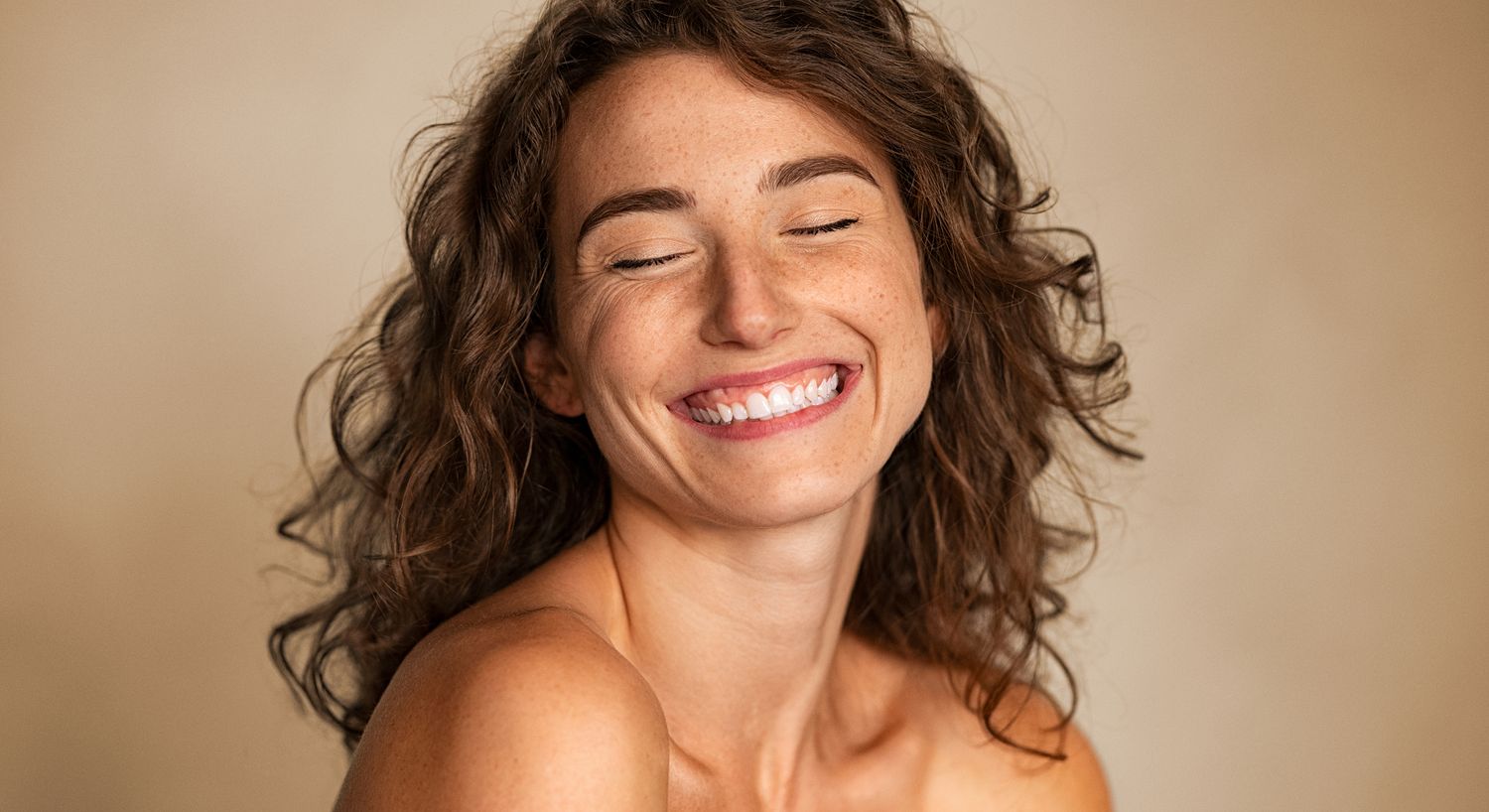 Smiling woman with curly hair and freckles.