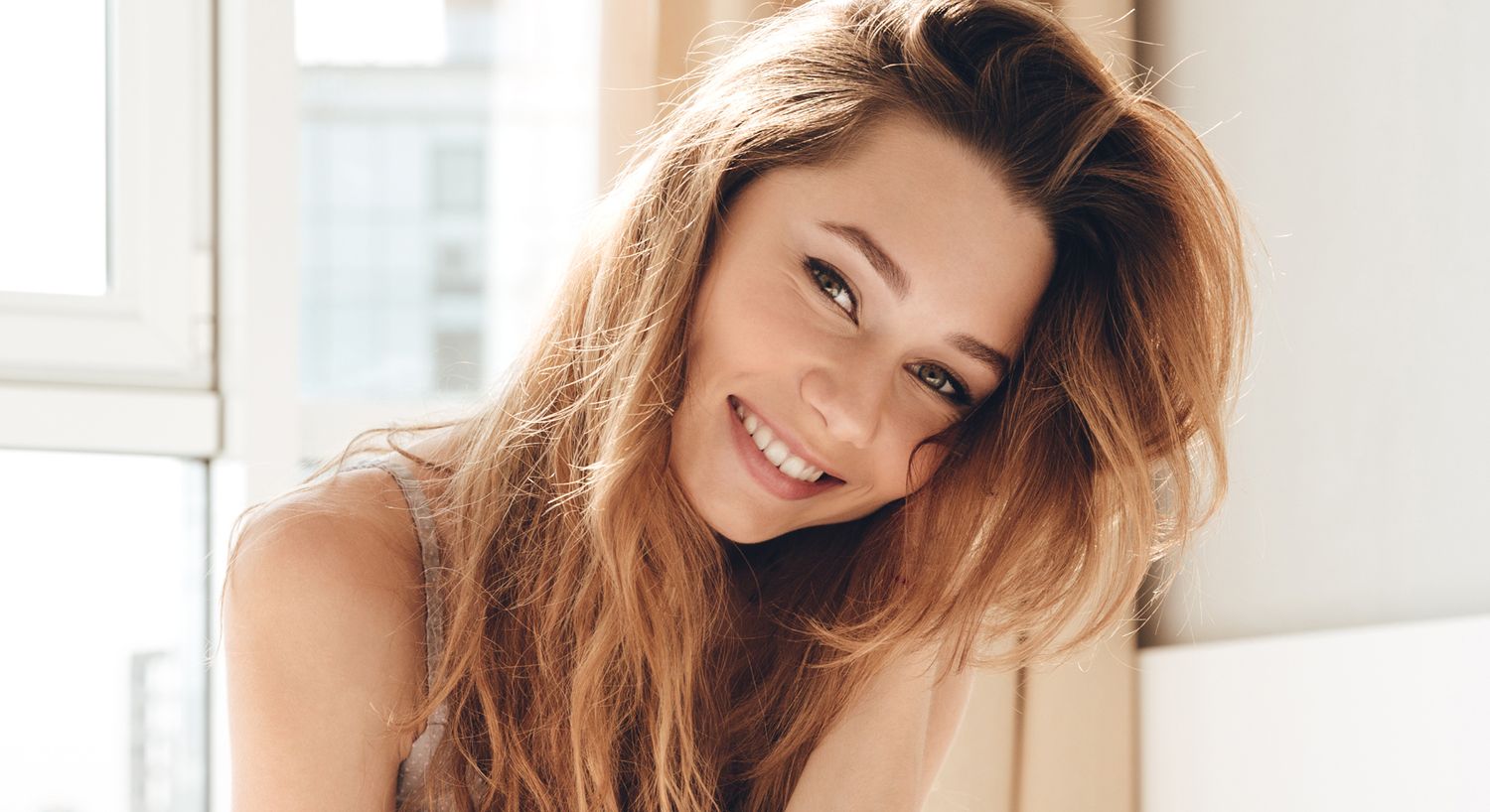 Smiling woman with long hair in bright setting.